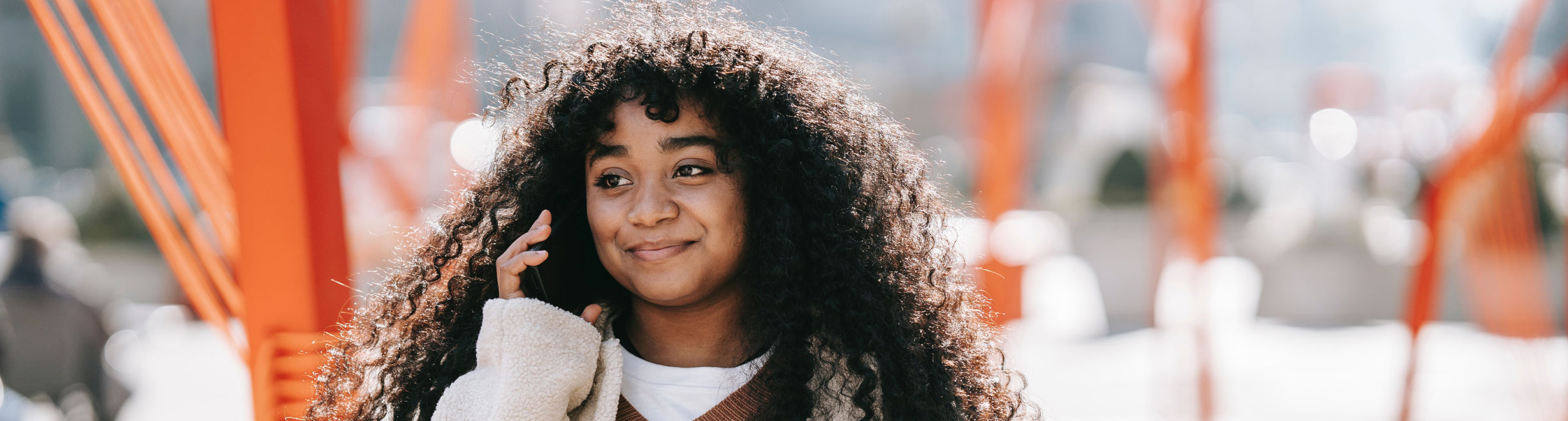 Jeune personne souriant à l’extérieur et utilisant un téléphone pour faire un changement en faveur de sa santé mentale lors de l’événement Bell Cause pour la cause 2024.