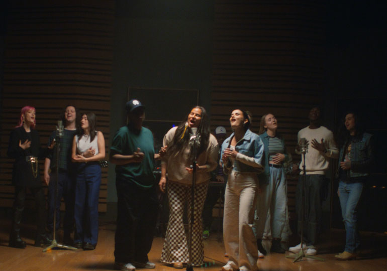 Un groupe d’artistes sur scène qui chantent l’hymne « Libère tes émotions ».